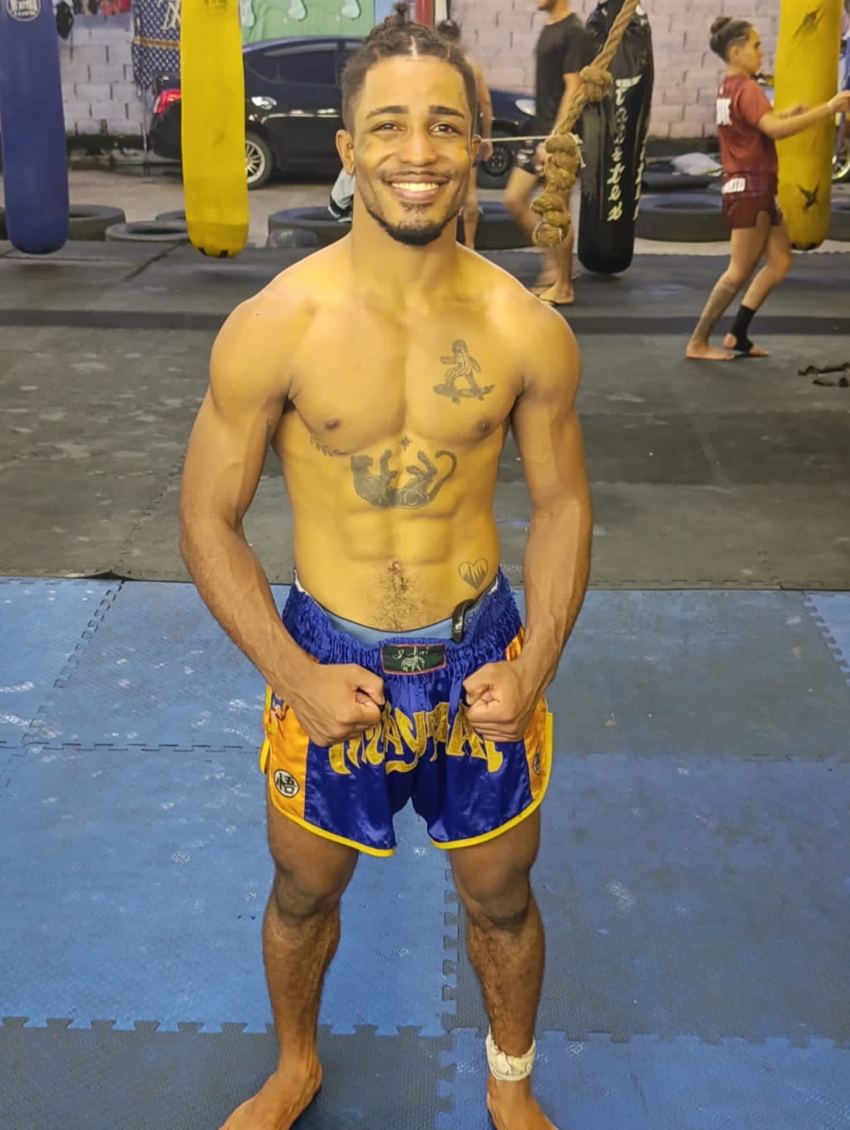 Christofer sorrindo em dia de treino, de shorts azul e amarelo