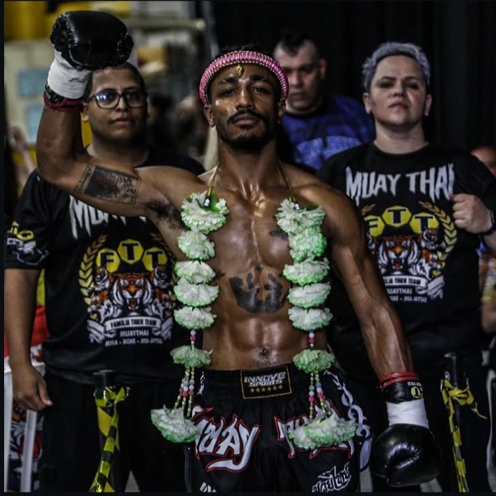 Christofer ergue a luva na entrada da luta, com a equipe Família Tiger Team ao fundo
