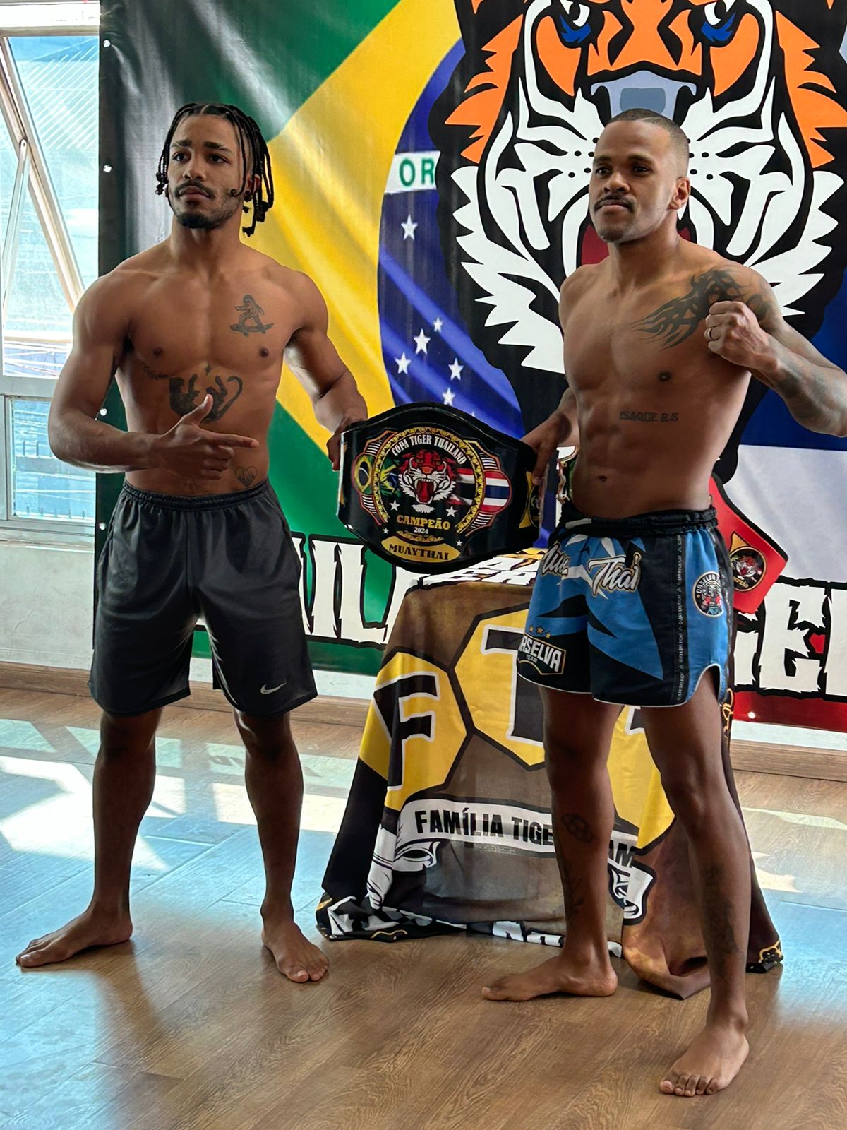 Encarada de pesagem com o cinturão da Copa Tiger Thailand, diante do banner da Família Tiger Team